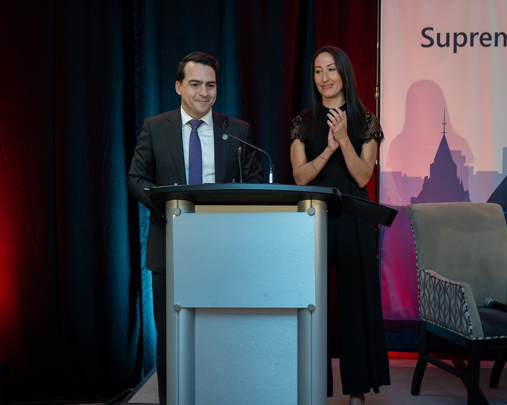 Les modérateurs Justin Robichaud et Laura Cutler debout à un podium 