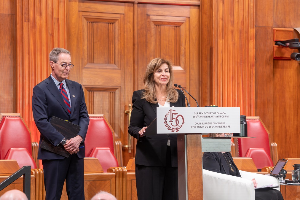 La juge Andromache Karakatsanis parle debout à un podium, accompagnée du juge Nicholas Kasirer