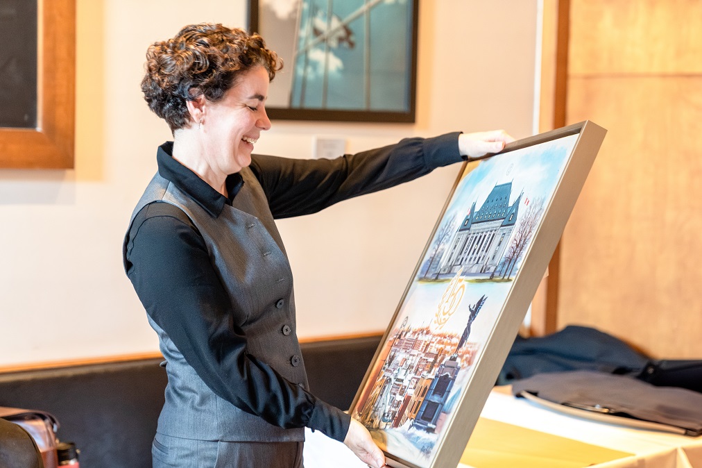 La doyenne de la Faculté de droit, Marie-Pierre Robert, admire une peinture donnée en cadeau par la Cour suprême.