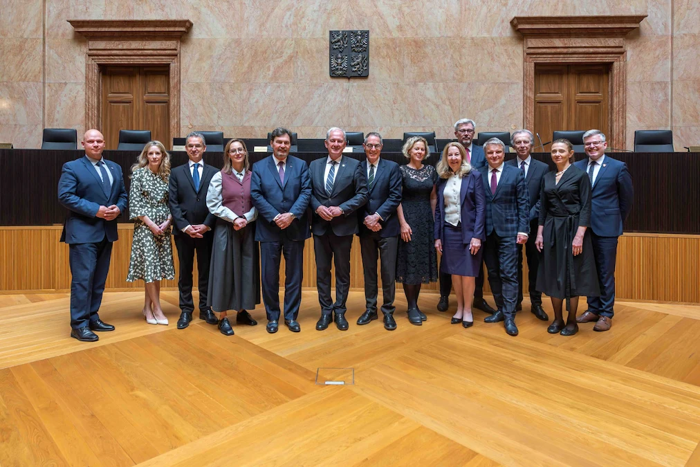 Photo de groupe du juge en chef avec les juges et des représentants de la Cour constitutionnelle de la République tchèque, dans une salle d'audience.