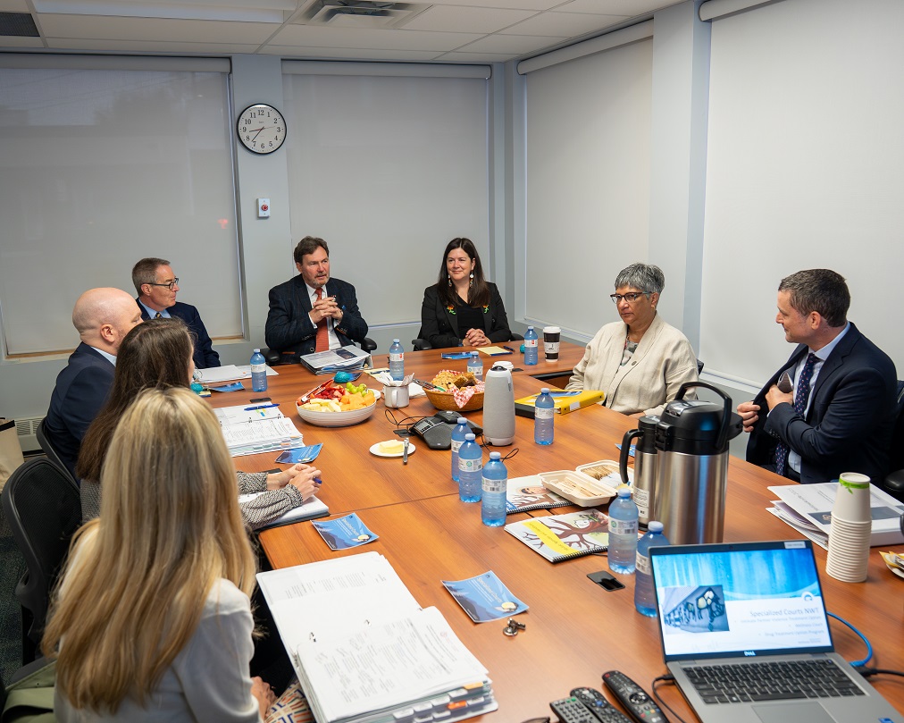 Le juge en chef Wagner et les juges Kasirer et O’Bonsawin assis à une table avec des employés de la Wellness Court et de la Intimate Partner Violence Treatment Option Court.