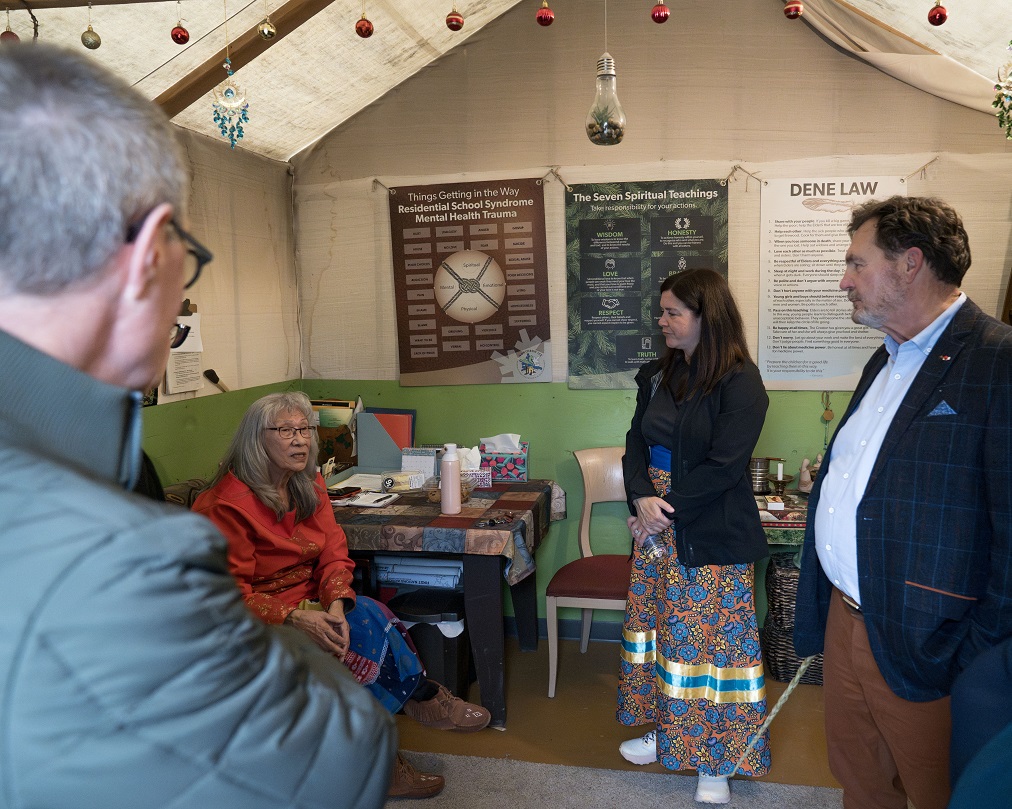 Le juge en chef Wagner et les juges Kasirer et O’Bonsawin écoutent une Aînée parler dans une tente.