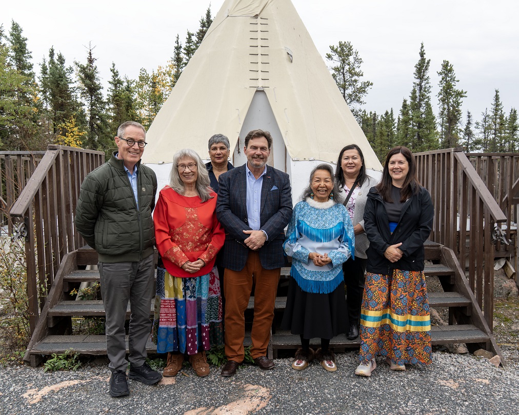 Une photo de groupe du juge en chef Wagner, du juge Kasirer, de la juge O’Bonsawin, de la juge en chef Smallwood et de la juge en chef Khullar avec des Aînés de la Arctic Indigenous Wellness Foundation devant une tente.