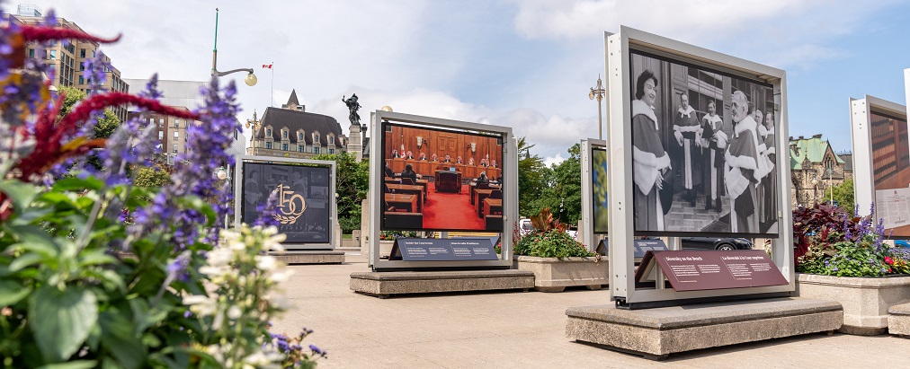 De grands panneaux photo exposés sur le pont Plaza avec la Colline du Parlement en arrière-plan
