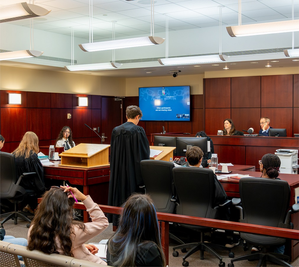 Des étudiants en toges d’avocats dans une salle d’audience, avec les juges assis au banc