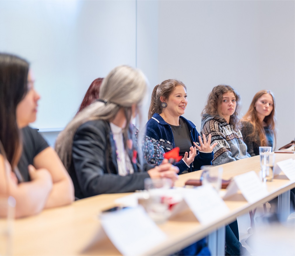 Des étudiantes et des professeurs discutent assises à une table